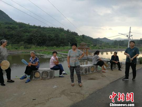 南文都村民坐在优美的荷花池边乘凉聊天。　李晓伟 摄